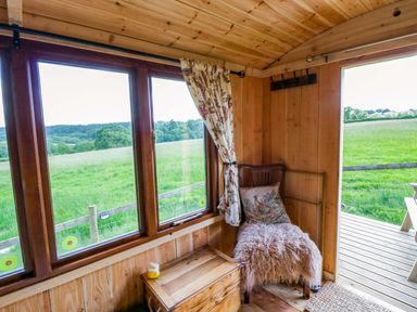 A snug area with a window, wooden chair, and box at The Little Shepherds Hut with a View Builth Wells