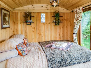 A bedroom with a bed and wooden walls at The Little Shepherds Hut with a View Builth Wells