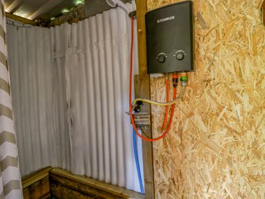 A bathroom with a water heater mounted on the wall at The Little Shepherds Hut with a View Builth Wells