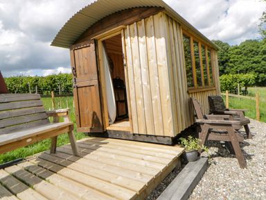 A wooden hut with a bench and chairs outside at The Little Shepherds Hut with a View Builth Wells