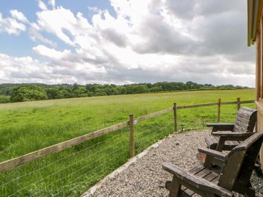 An outdoor area with wooden chairs overlooking a field at The Little Shepherds Hut with a View Builth Wells