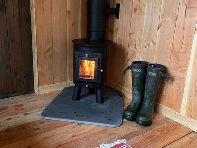 A stove with fire and boots at The Little Shepherds Hut with a View near Newbridge-On-Wye