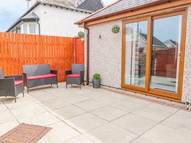 An outdoor area with seating and a sliding door at Smithy Cottage in Cemaes Bay