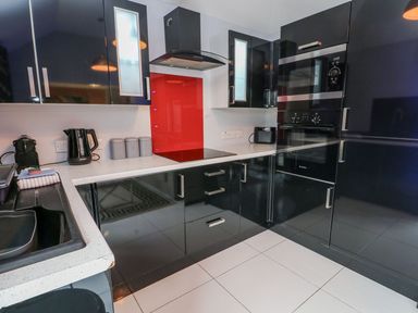 A kitchen with black cabinets and appliances at Smithy Cottage in Cemaes Bay