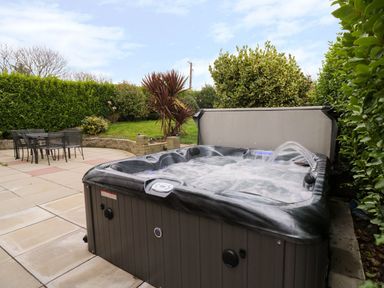 A garden with a hot tub and outdoor seating at Gwelfor in Cemaes Bay