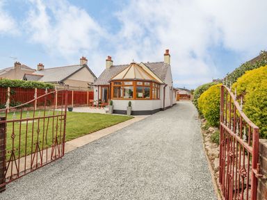 A house with a gravel driveway and a conservatory at Trefin Cemaes Bay