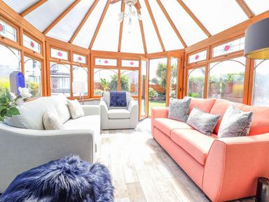 A conservatory with sofas and plants at Trefin in Cemaes Bay