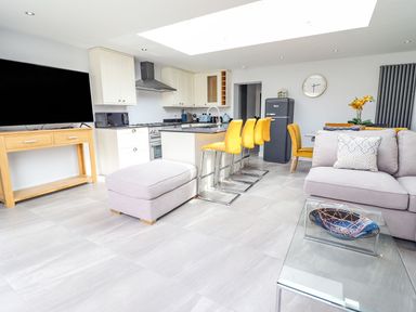 A living room with a kitchen island and bar stools at Trefin in Cemaes Bay