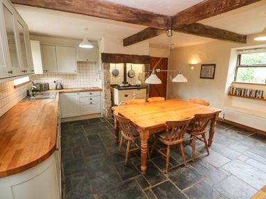 A kitchen with a table and chairs at Swallow Cottage in Helston