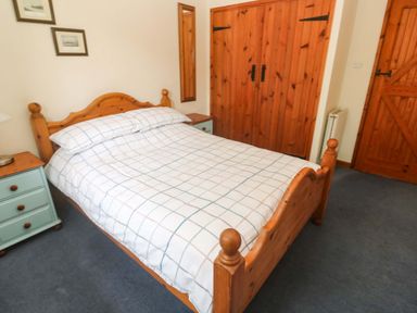 A bedroom with a bed and bedside table at Swallow Cottage in Helston