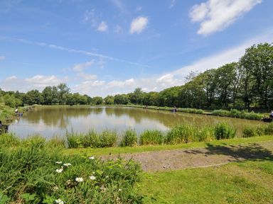 A pond with people fishing and greenery at Caravan in Dolton