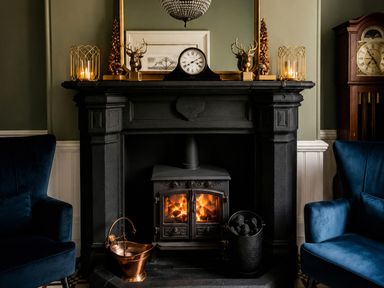A fireplace with a clock and armchairs in a living room at Chowdene Lodge Estate