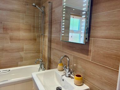 A bathroom with a bathtub, sink, and shower at Lakeside Retreat in Newton Abbot
