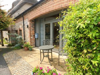An outdoor seating area with a table and chairs at Frome Gazey Barn in Frampton