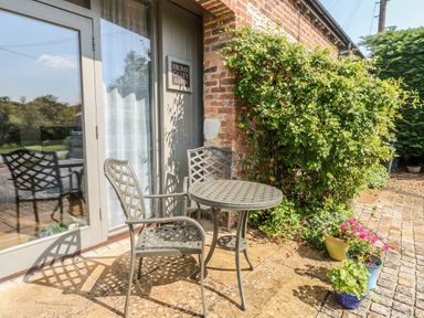 An outdoor seating area with a table and chairs at Frome Gazey Barn in Frampton