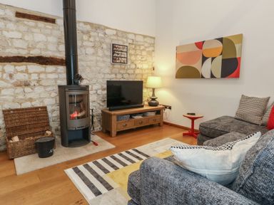 A living room with a television and stove at Frome Gazey Barn in Frampton