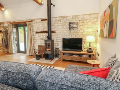 A living room with a sofa and television at Frome Gazey Barn in Frampton