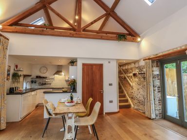 A kitchen with a dining table and chairs at Frome Gazey Barn in Frampton