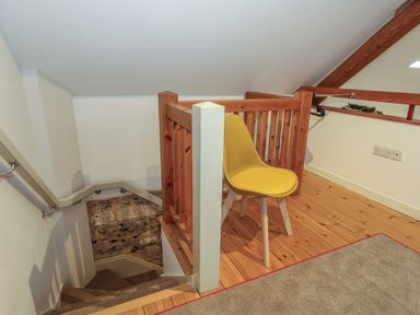 A hallway with a staircase and a chair at Frome Gazey Barn in Frampton