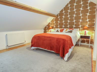 A bedroom with a bed, bedside tables, and a radiator at Frome Gazey Barn in Frampton