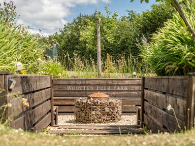 A garden with a fire pit and wood enclosure at Luxury Safari Lodge Sleeps 4/6 Deer Park Dogs Ok Zeal Monachorum near Bow