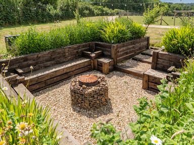 A garden area with wood seating and a fire pit at Luxury Safari Lodge Sleeps 4/6 Deer Park Dogs Ok Zeal Monachorum near Bow
