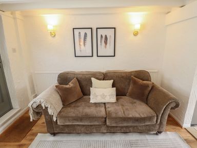A living room with a sofa, wall art, and a radiator at Pax Cottage