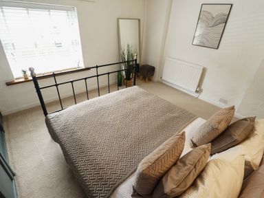 A bedroom with a bed, pillows, and a window at Pax Cottage
