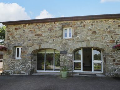 A stone building exterior with windows and a door at The Cart House in Pontsian