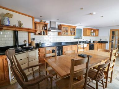 A kitchen with a dining table and chairs at Yr Hen Felin in Boncath