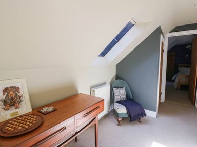 A hallway with a chair and side table at Yr Hen Felin in Boncath