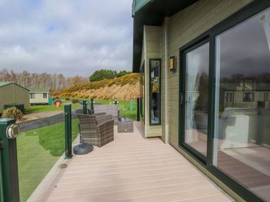 A deck area with chairs and a table at 56 The Stables Pwllheli