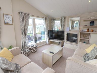 A living room with a television and coffee table at 56 The Stables Pwllheli