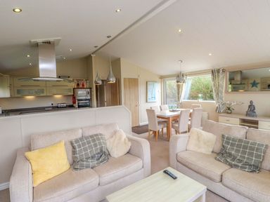 A living room with sofas and a dining area at 56 The Stables in Pwllheli