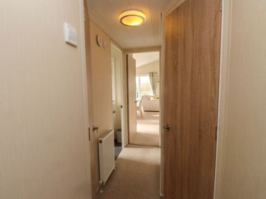 A hallway with doors and a radiator at 56 The Stables in Pwllheli