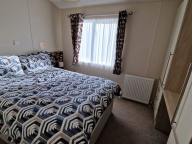 A bedroom with a bed and curtains at 56 The Stables in Pwllheli