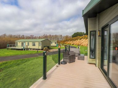 An outdoor view of caravans on a grassy area at 56 The Stables in Pwllheli