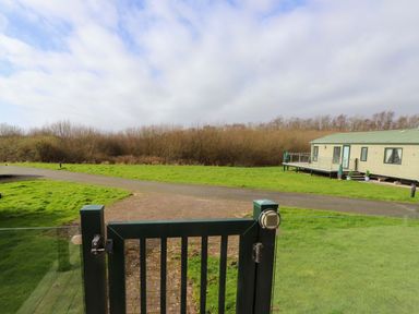 An outdoor area with a gate leading to a caravan at 56 The Stables in Pwllheli