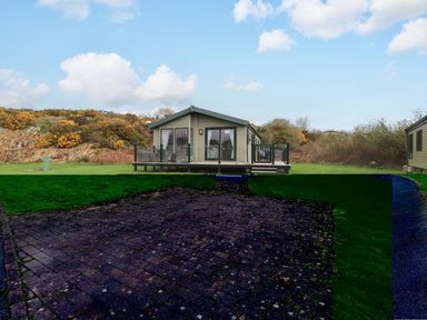 A house with a deck and grass area at 56 The Stables in Pwllheli