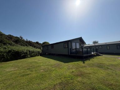 A cabin with a deck on grass at The Stables in Pwllheli