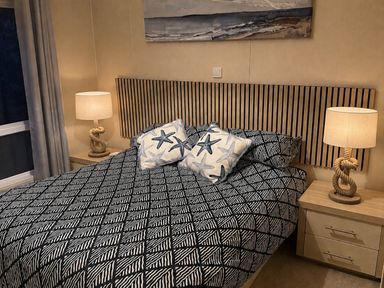 A bedroom with a bed, bedside tables, and lamps at The Stables in Pwllheli