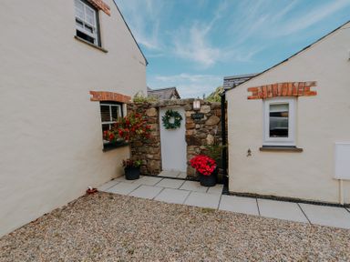 An entrance with stone wall and flowers at Ty Cosy in St Davids