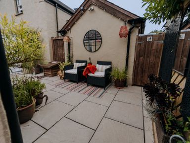 An outdoor seating area with a round mirror and planters at TyCosy in St Davids