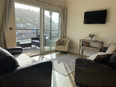 A living room with a TV and balcony view at Rivercrest in Looe