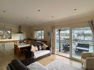A living room with a dining area and kitchen at Rivercrest in Looe