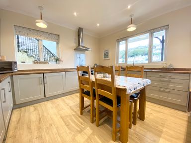 A kitchen with a wooden table and chairs at Rivercrest in Looe