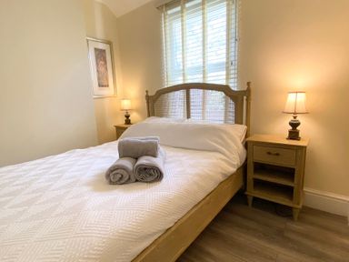 A bedroom with a bed, bedside table, and lamps at Nesden House
