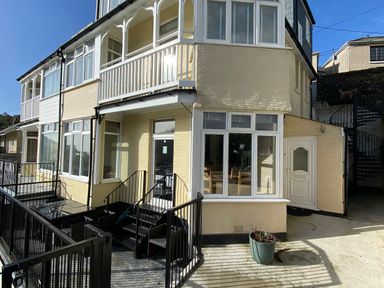 An exterior view of a house with balconies and stairs at Nesden House in Looe