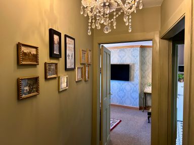 A hallway with framed pictures and a chandelier at Downton II in Alnwick