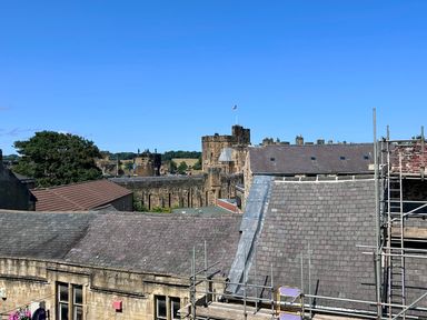A view of a castle and rooftops at Downton II in Alnwick